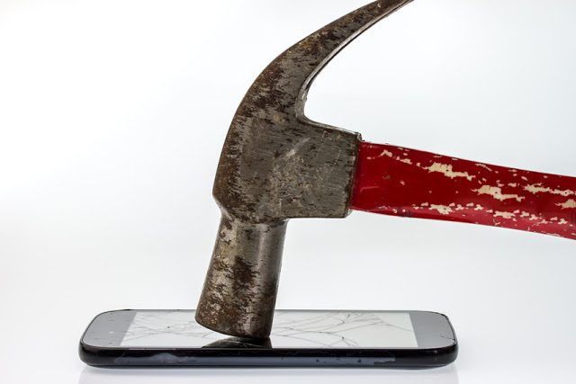 Hammer, mobile smartphone with broken screen and dust on screen.